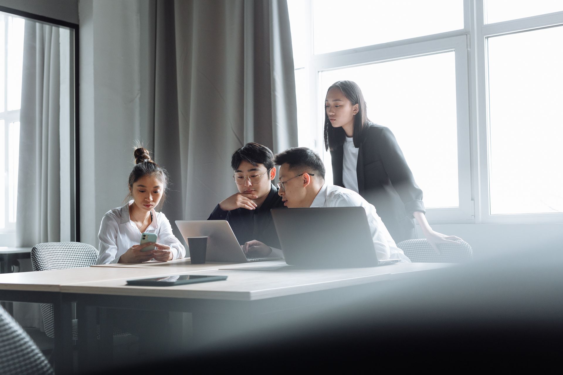 Four professionals collaborating around laptops in a bright office